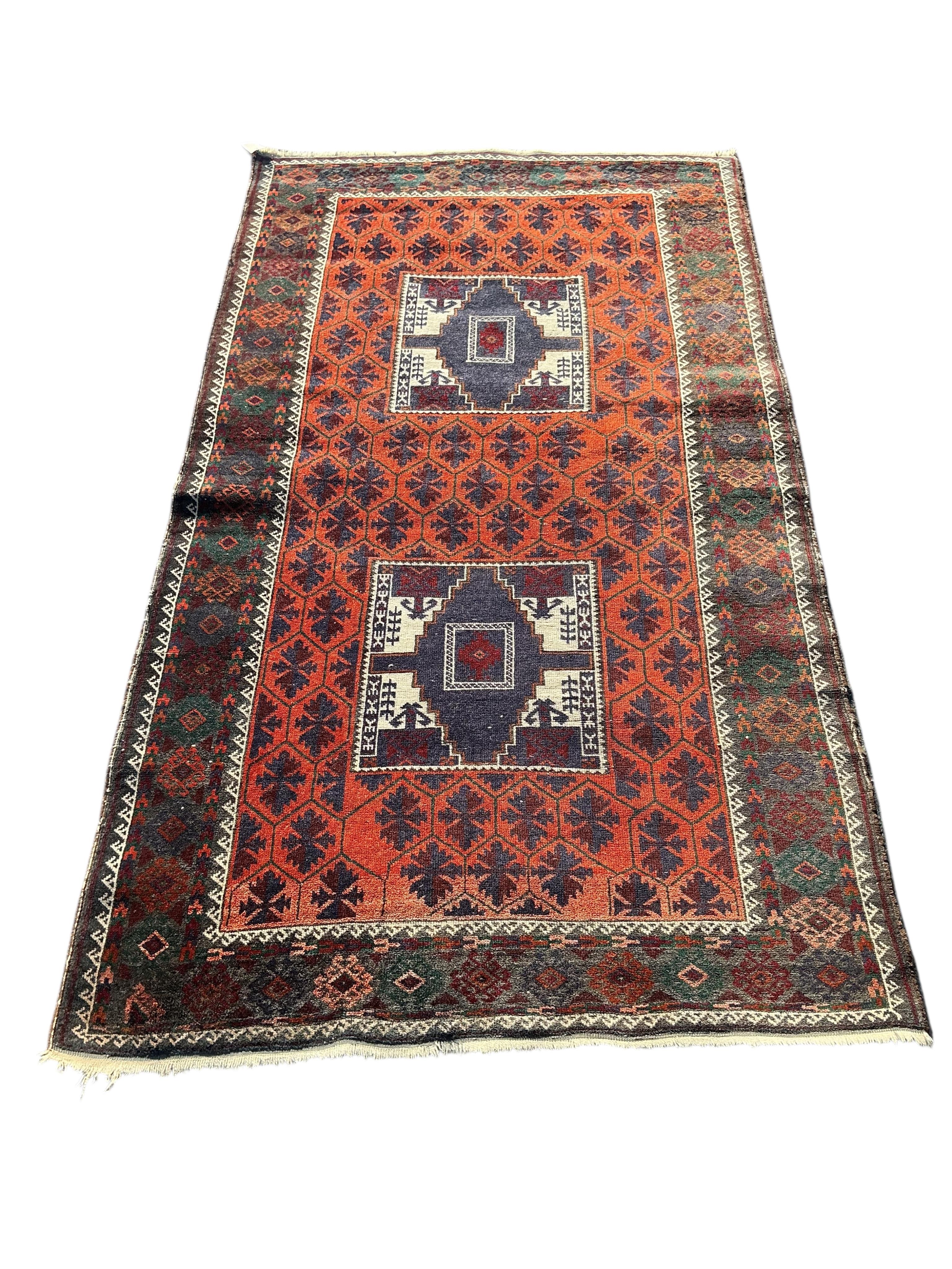 A Belouch twin medallion red ground rug, 194 x 107cm